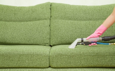 Person in Cleaning a Green Couch — Upholstery & Carpet Cleaning on the Sunshine Coast, QLD