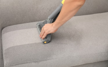 Person Vacuuming a Couch — Upholstery & Carpet Cleaning on the Sunshine Coast, QLD