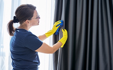 A Person Wiping a Black Silky Curtain — Upholstery & Carpet Cleaning on the Sunshine Coast, QLD