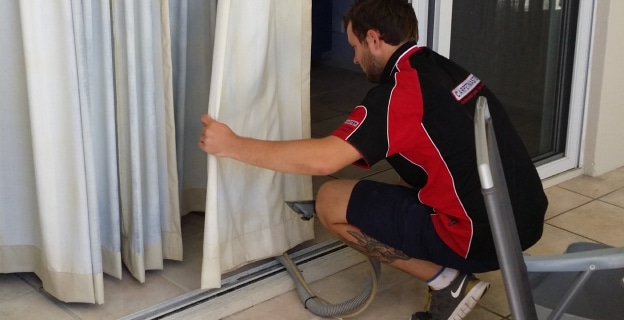 Man Cleaning Curtain Using Vacuum — Upholstery & Carpet Cleaning on the Sunshine Coast, QLD