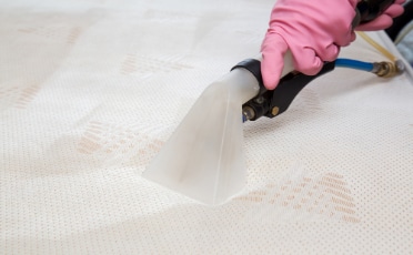 Person Using a Vacuum Cleaner to Clean Mattress — Upholstery & Carpet Cleaning on the Sunshine Coast, QLD