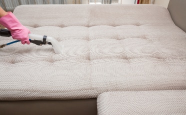 A Woman Using a Vacuum Cleaner on A Grey Mattress — Upholstery & Carpet Cleaning on the Sunshine Coast, QLD