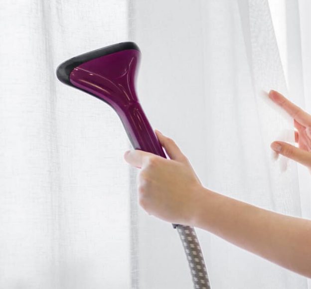 Woman Holds a Steamer for Curtains in Her Hand — Upholstery & Carpet Cleaning on the Marcoola, QLD
